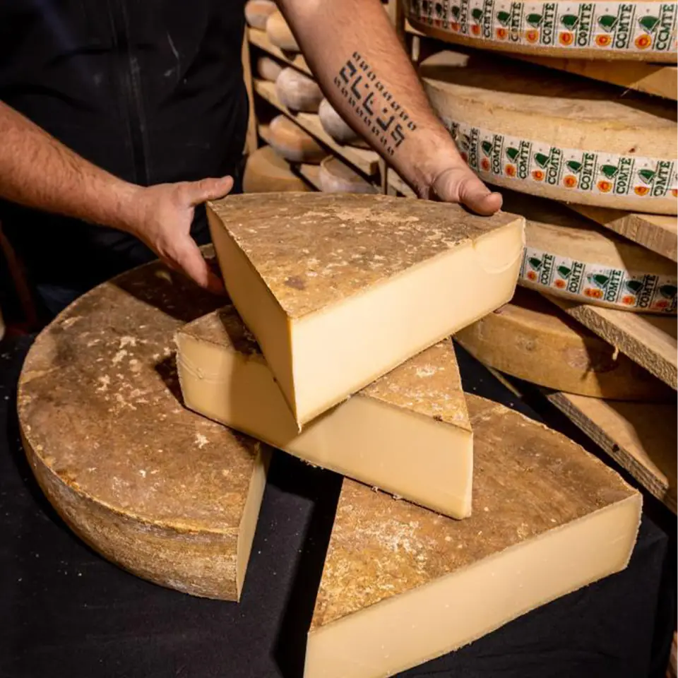 Freddy taille une meule de fromage dans la cave d'affinage